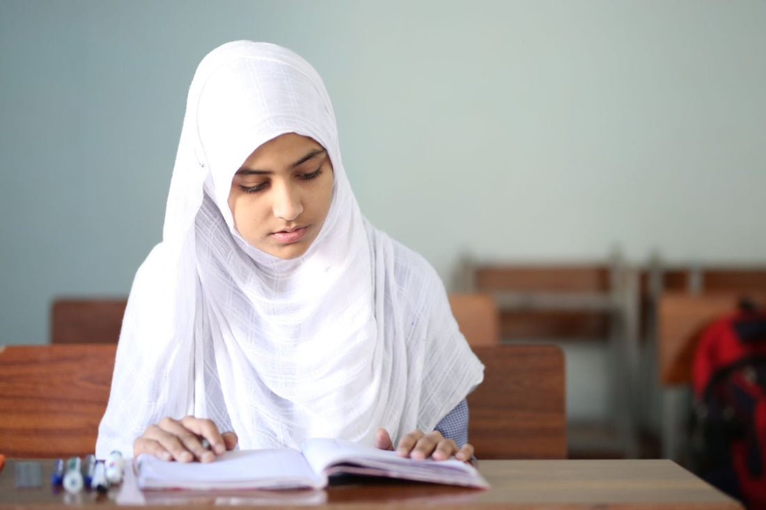 Muslim girl in a white hijab studying at her desk in class